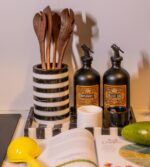 Bir kitap, bir bıçak, bir şişe yemeklik yağ ve modern siyah beyaz çizgili bir vazonun yer aldığı mutfak tezgahı.